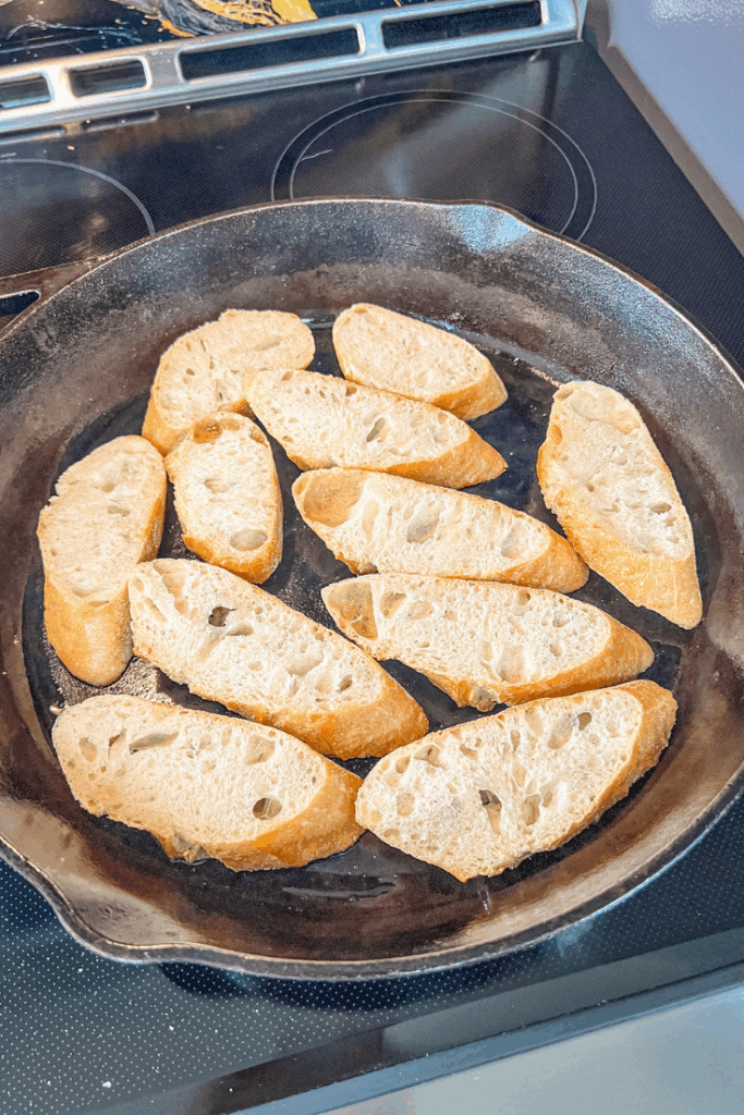 a pan filled with bread slices cooking on the stove