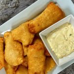 Finished beer batter fish on a white platter with homemade tartar sauce