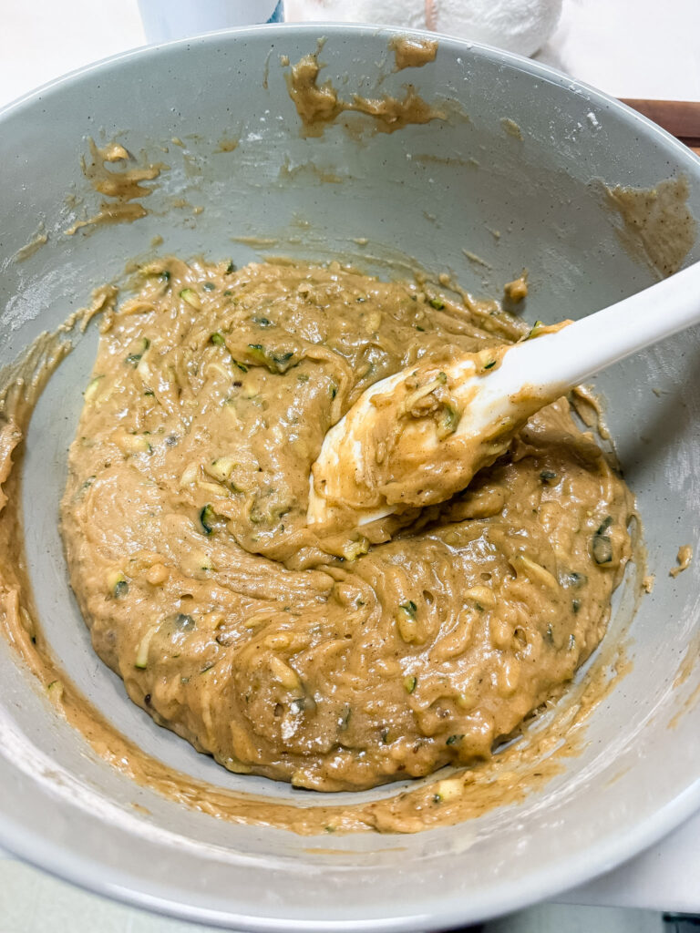 Finished zucchini bread batter in a large bowl showing green zucchini pieces throughout the brown mixture