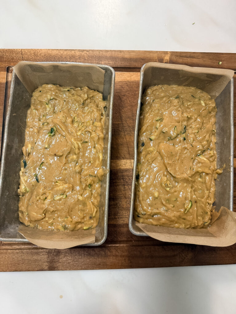 Two empty ungreased loaf pans lined with white parchment paper on a wooden cutting board