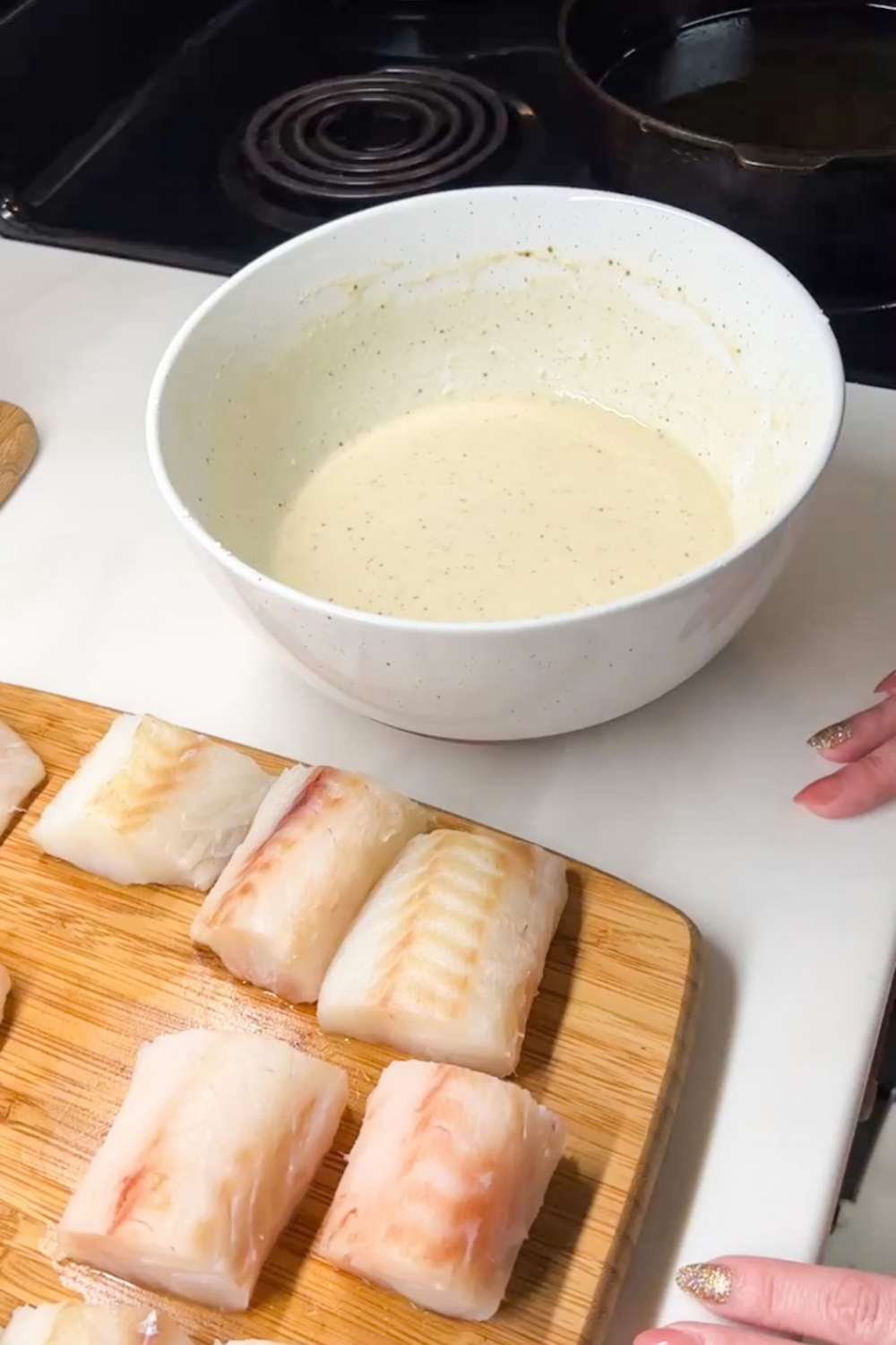 White fish fillets cut into pieces on cutting board for beer battered fish