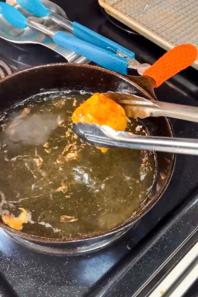 Golden beer battered fish being removed from oil after frying