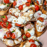 roasted tomato, avocado, and mozzarella crostini on a pink platter