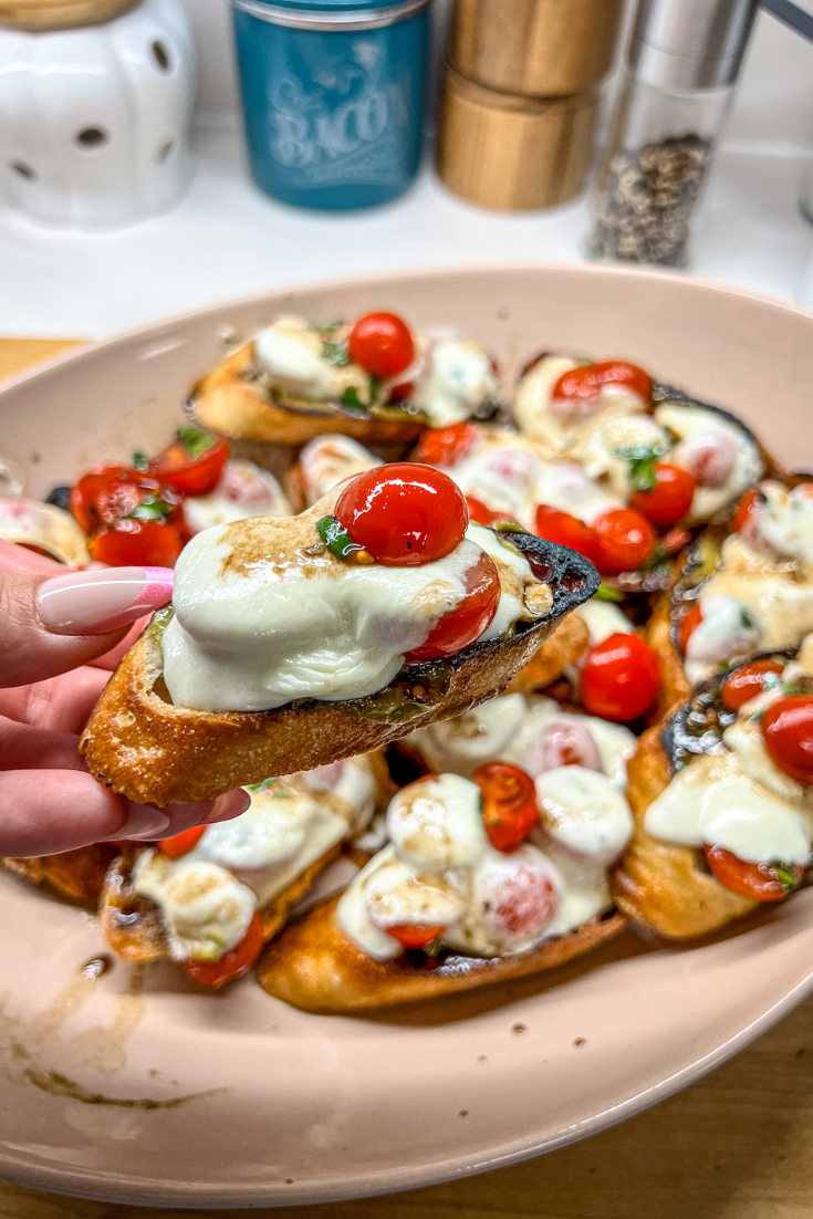 roasted tomato, avocado, and mozzarella crostini on a pink platter