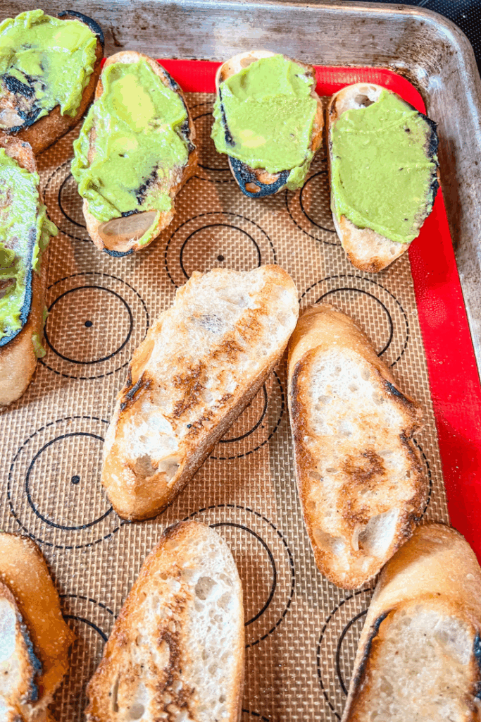 several slices of bread on a baking sheet with some with avocado