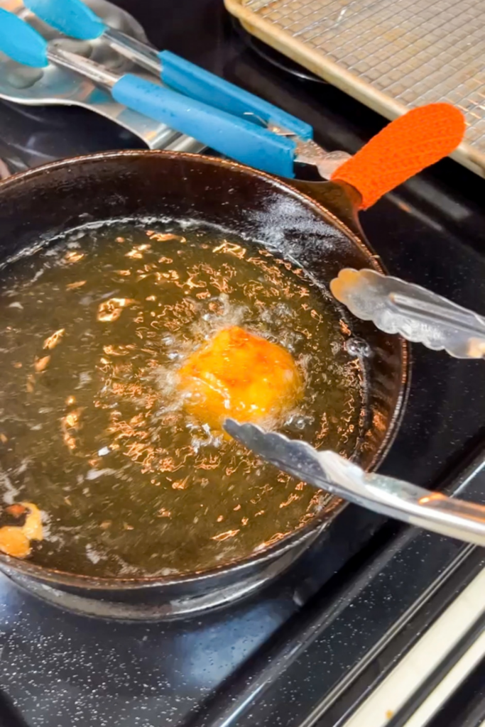 Turning crispy beer battered fish in hot oil with tongs