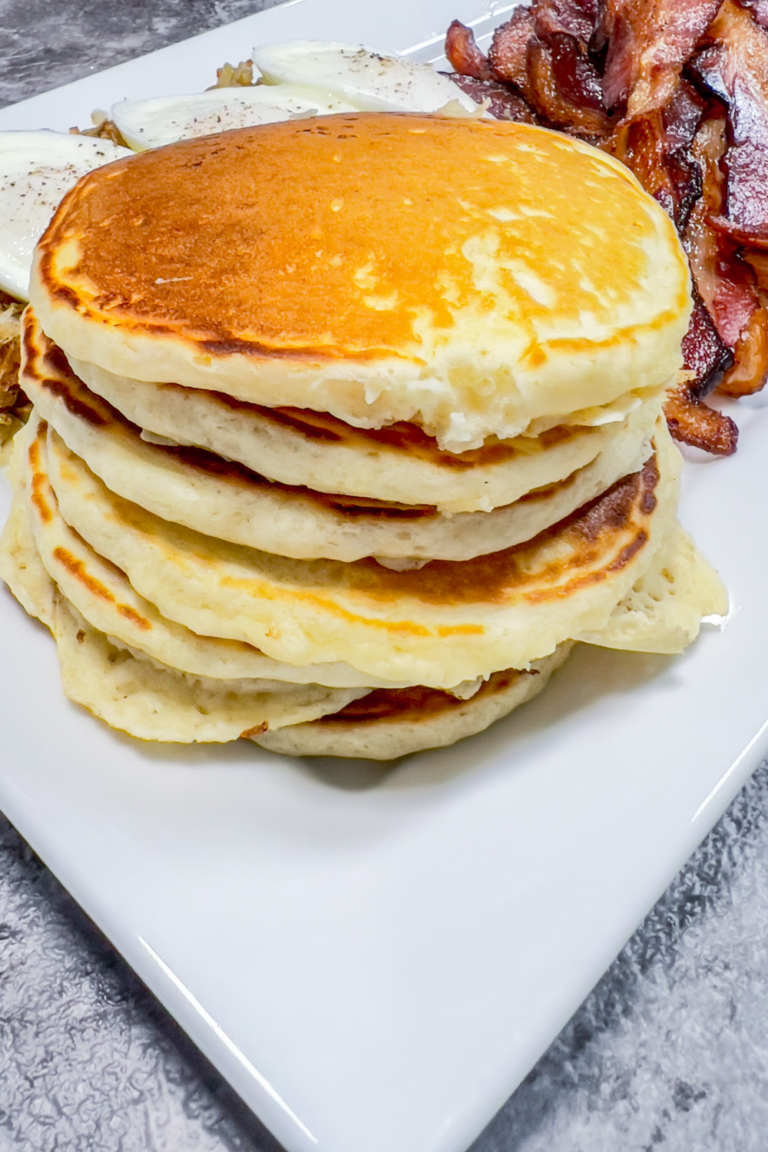 Finished Pancakes on a platter with bacon, eggs and hashbrowns