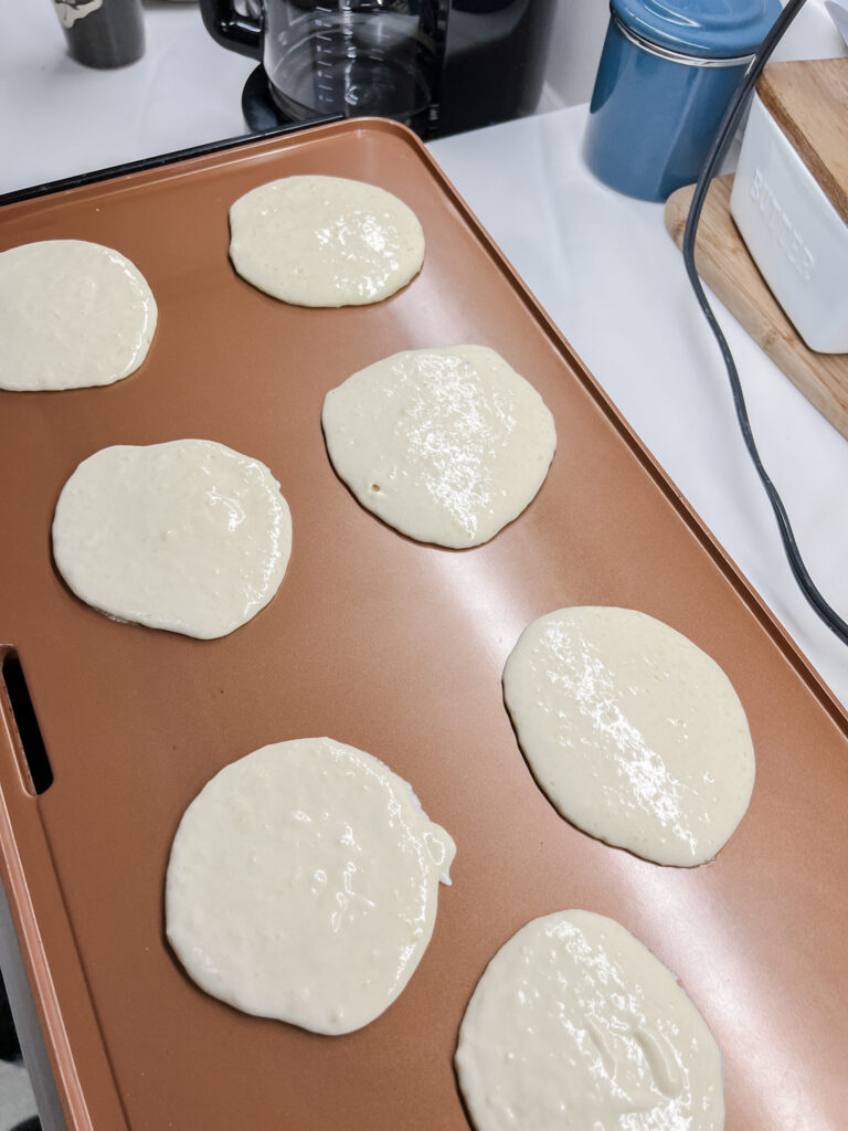 pancakes on the griddle before being flipped showing bubbles.