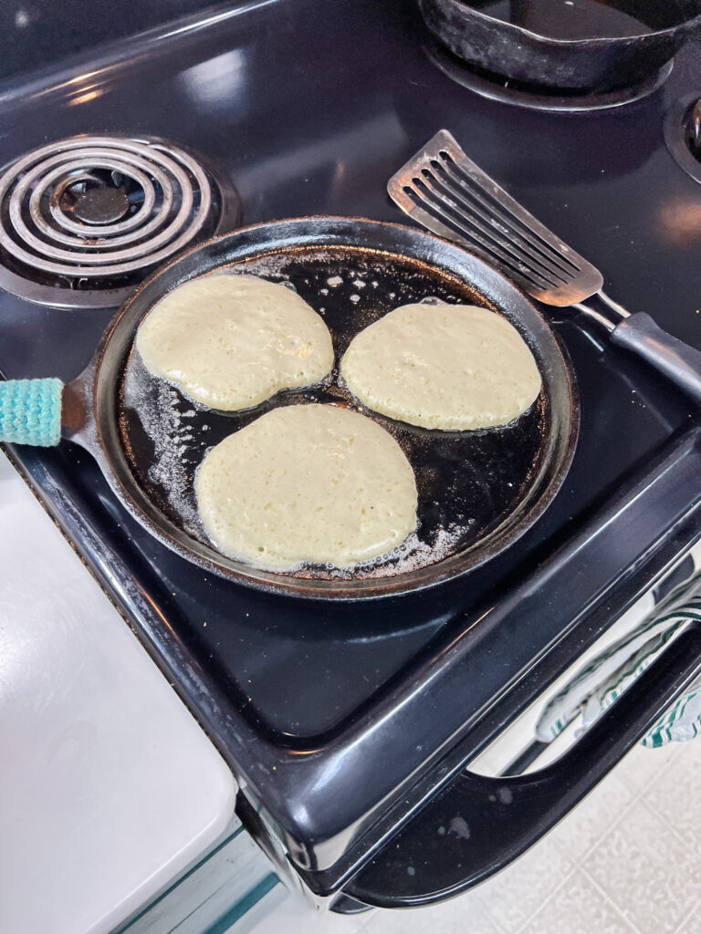 pancakes on the cast iron before being flipped showing bubbles.