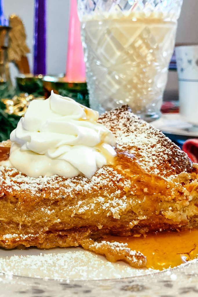 French toast with Syrup poured onto it. a slight pooling of maple syrup at the bottom and topped with homemade whipped Cream.