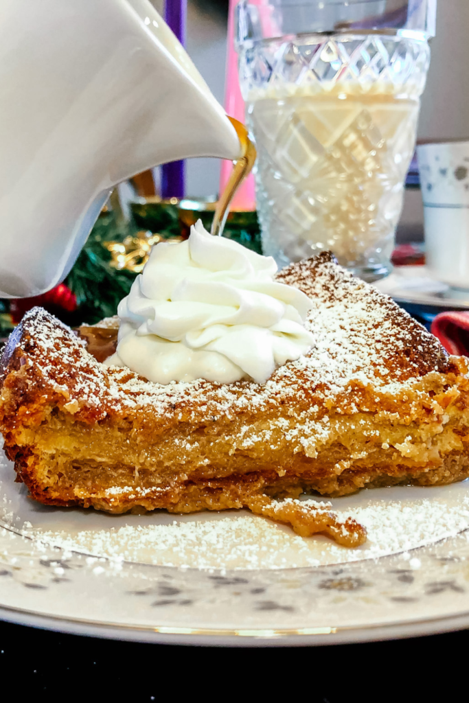 Overnight French Toast with homemade whipped cream and syrup being poured over it.