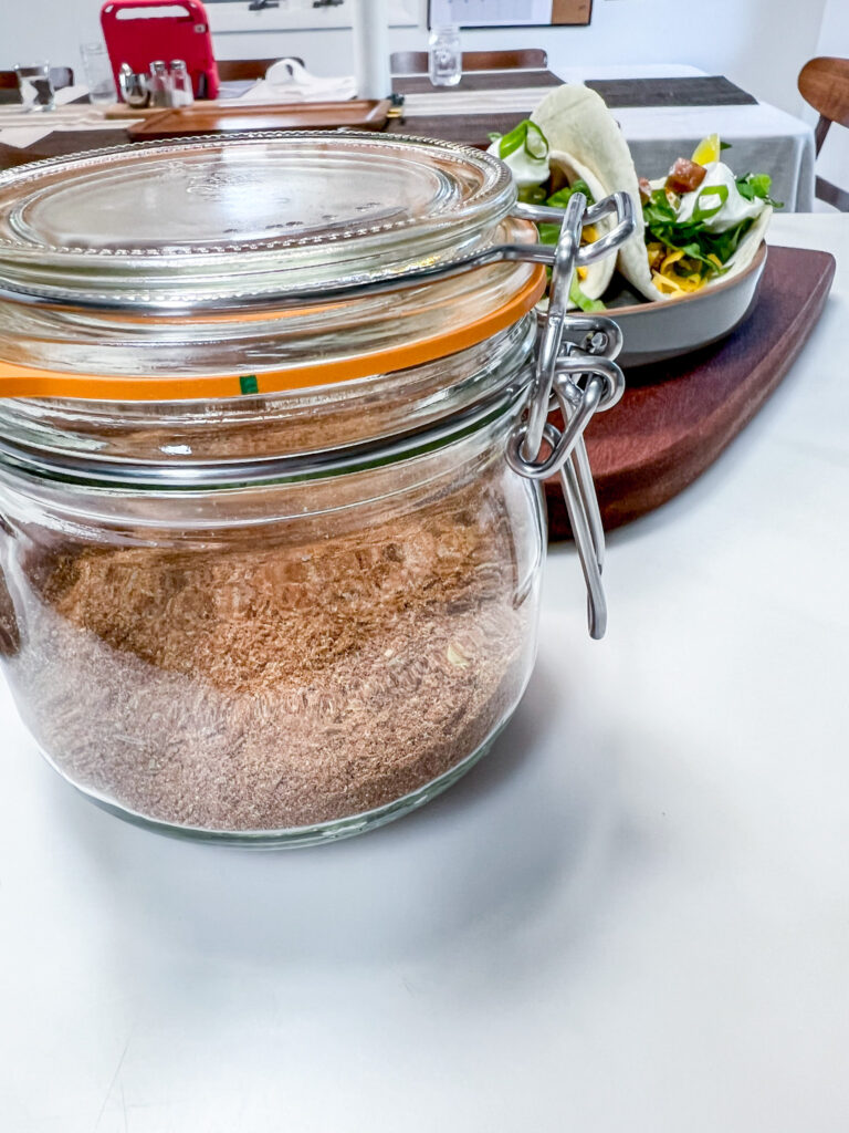 a jar of taco seasoning sits on a counter next to a plate of tacos