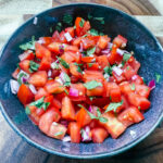 pico de gallo in a bowl on a wooden cutting board