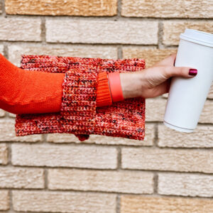 showing the strap around the arm while holding a coffee.