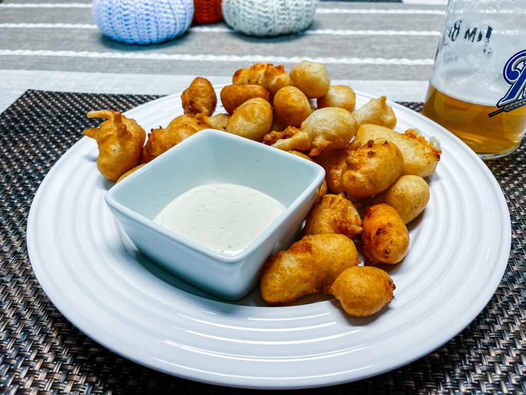Cheese curds around a small square bowl of ranch dressing