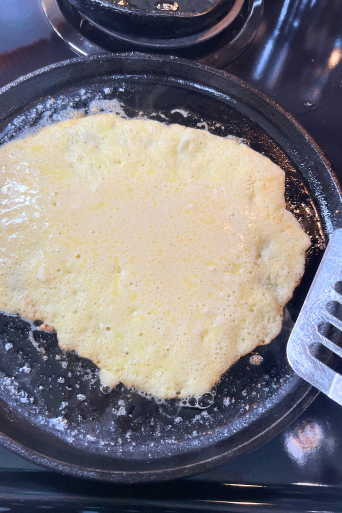 a pancake is being cooked in a pan with a spatula