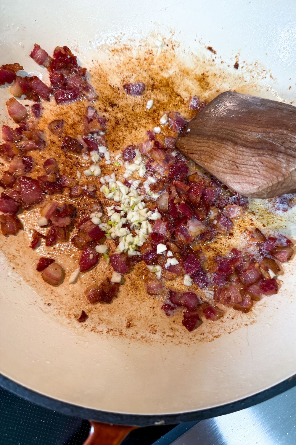 Adding garlic to cooked bacon in pan for pasta