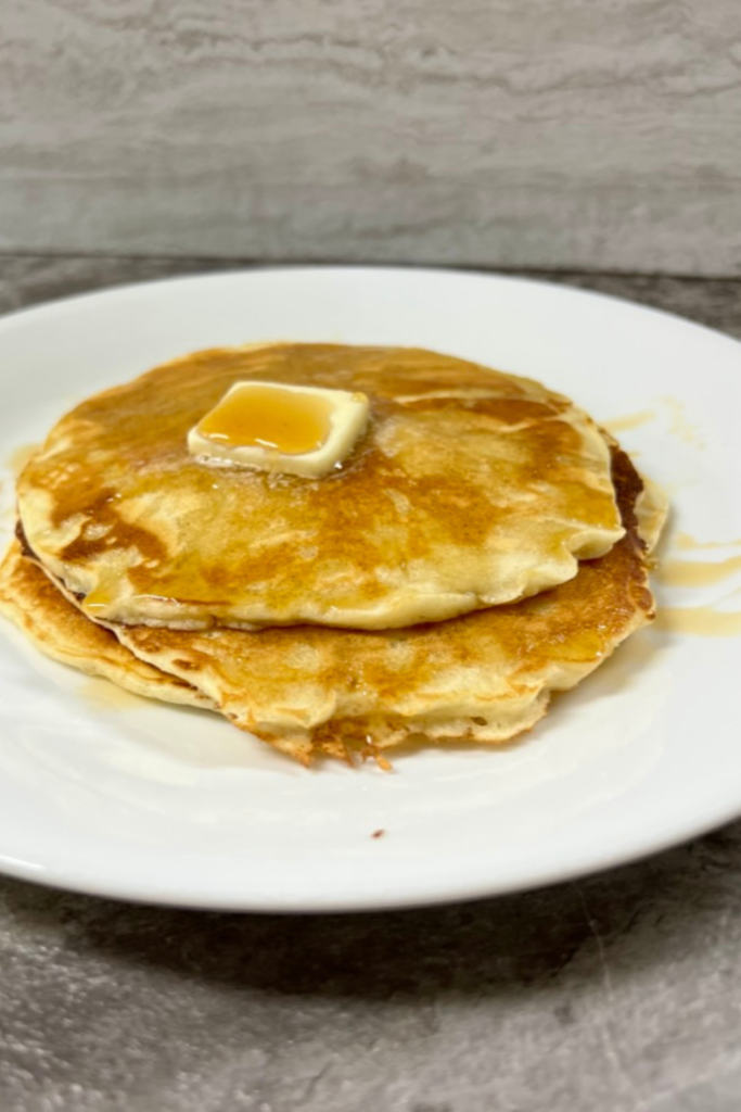 pancakes on a white plate with butter and syrup