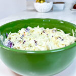 close up of finished Coleslaw in a green ceramic bowl.