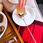 a s'more being made using graham crackers, marshmallow and a peanut butter cup.