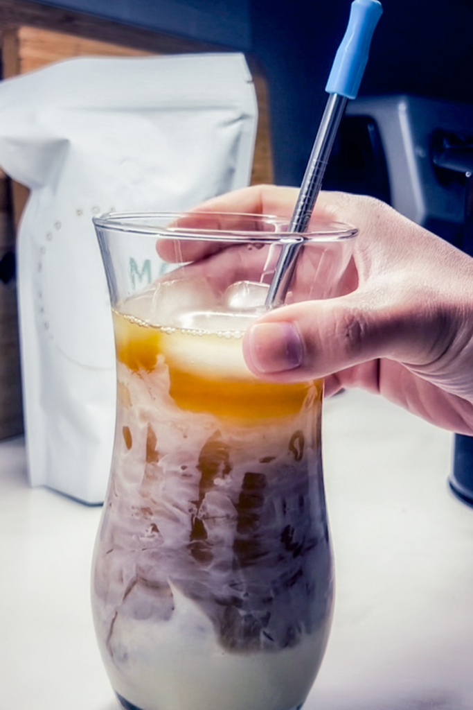 Image is of a glass of coffee with sweetened condensed milk and a straw as I'm grabbing it.