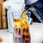 Pouring the Cold brew into the glass of ice and sweetened condensed milk