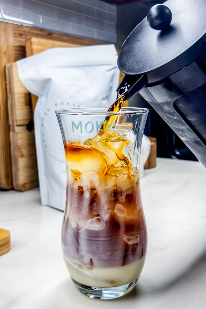 Pouring the Cold brew into the glass of ice and sweetened condensed milk