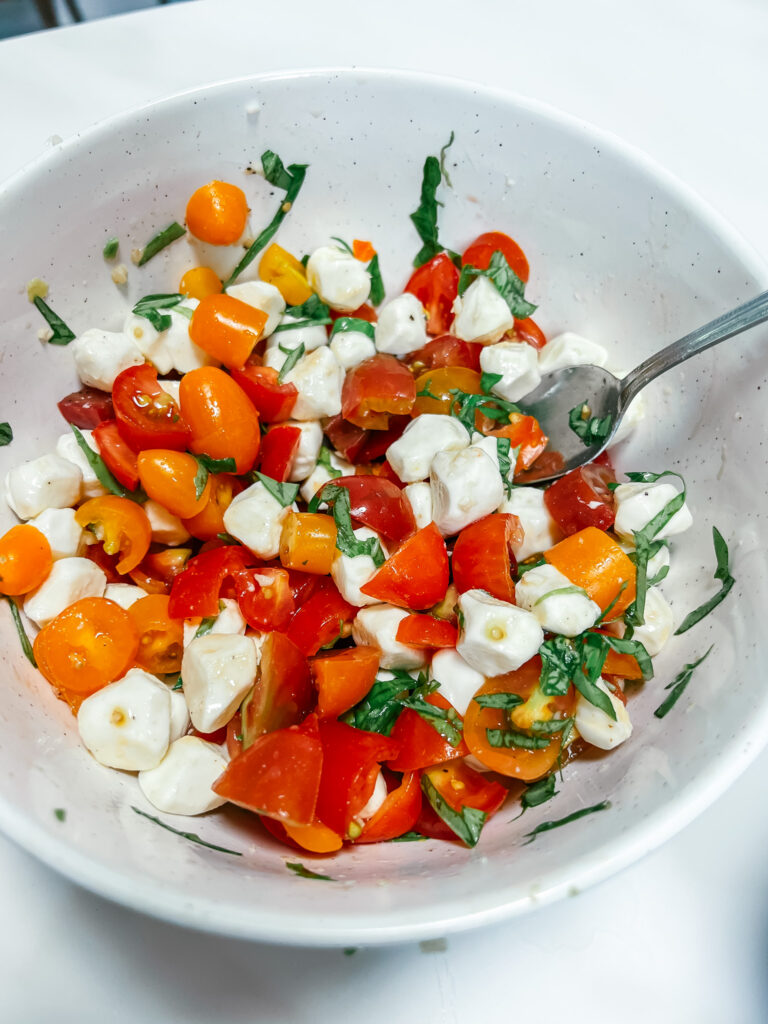Finished tomato mozzarella salad in a white ceramic bowl