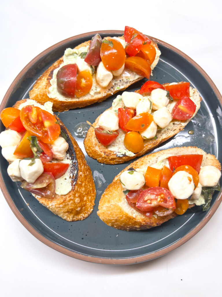 Finished salad on top of freshly made crostinis on a ceramic plate.