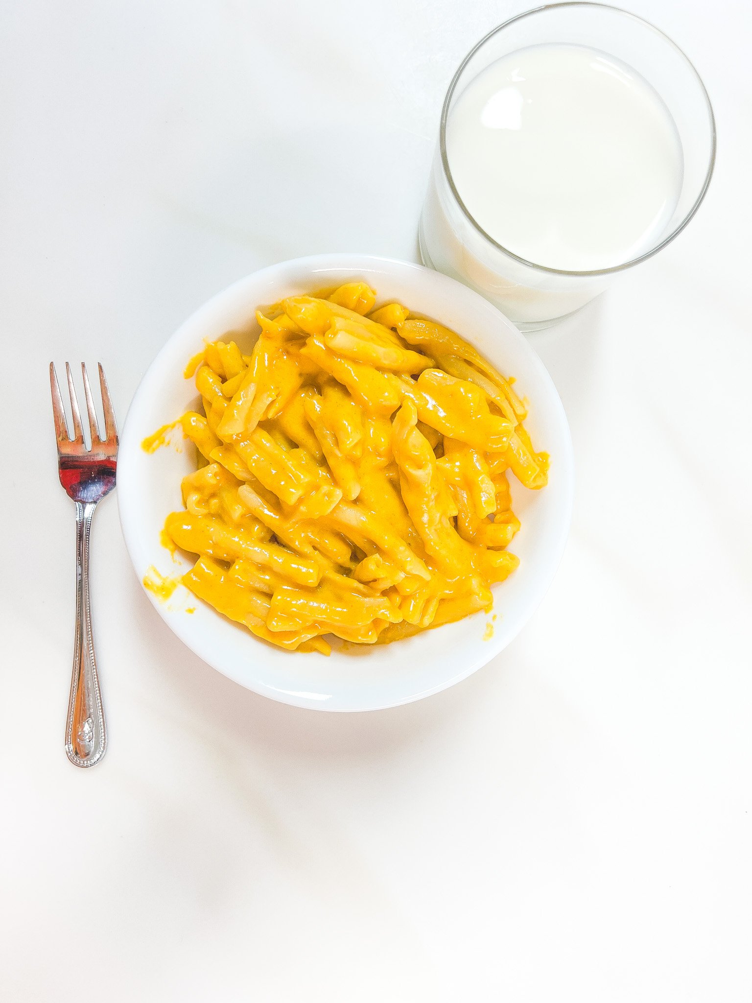 Healthy stovetop mac and cheese with casarecce pasta and creamy orange cheese sauce, served with milk