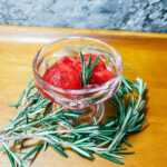 Finished Cranberry Granita in a small dish with rosemary.