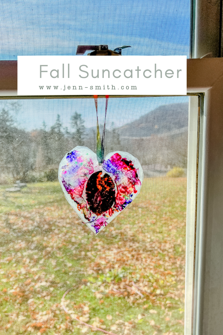 Fall Suncatcher Featured Image: Image is of the finished Sun Catcher in a heart shape, on a window.