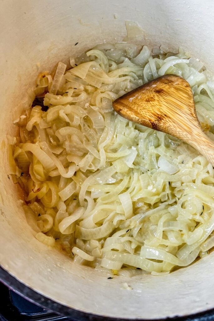 cooked sliced onions, chopped garlic, and thyme, in a cast iron pot on the stove