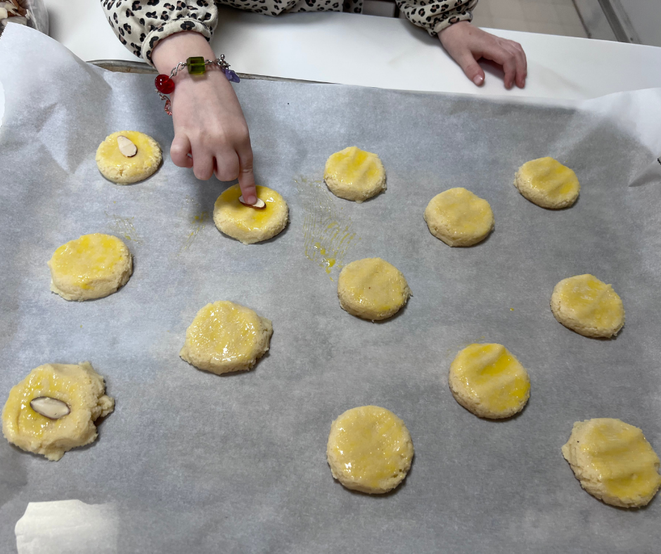 kid hand pressing almond slice on cookie