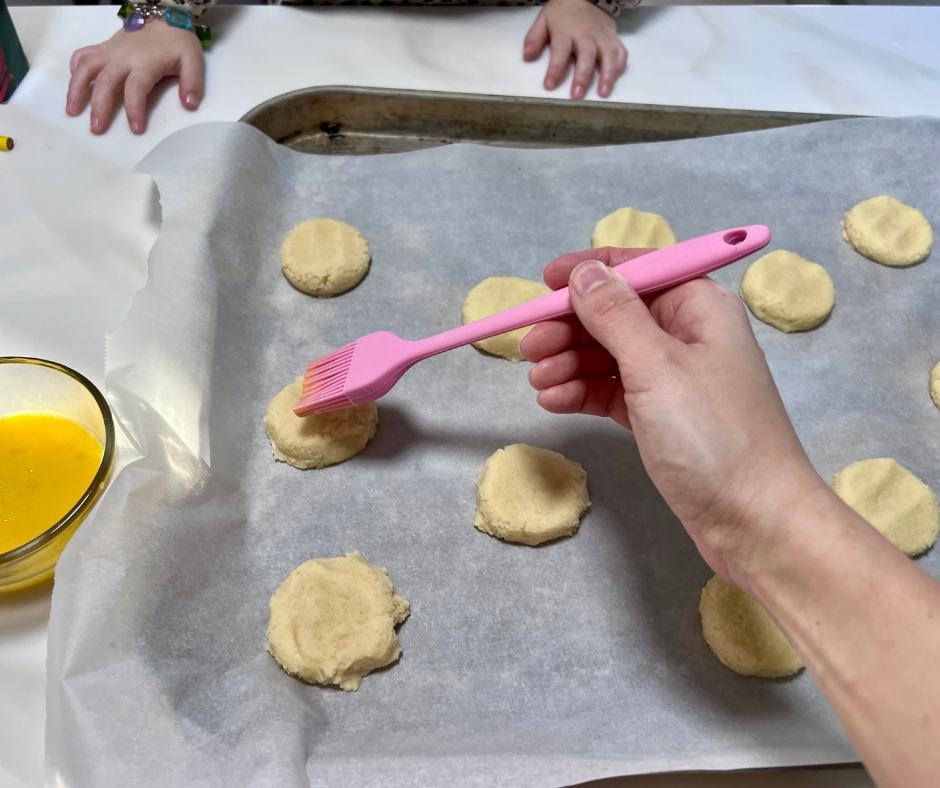 my hand brushing egg wash on a cookie