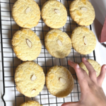 gluten free Almond Cookies on a cooling rack and one of my kids reaching for one.