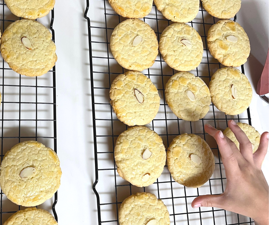 gluten free Almond Cookies on a cooling rack and one of my kids reaching for one.