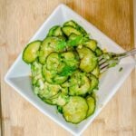 Asian Cucumber Salad in a square bowl on a bamboo cutting board