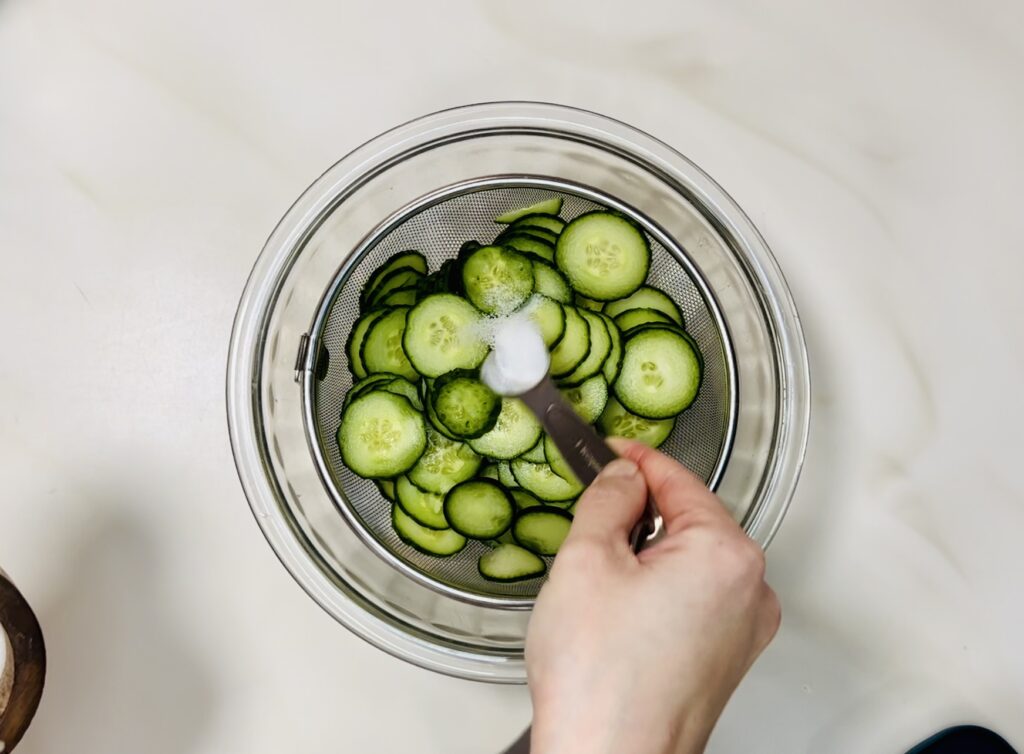 Salt being shaken over the cucumbers.