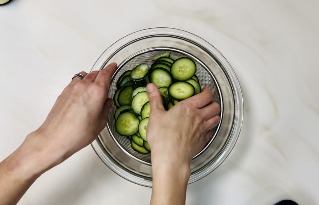 me tossing the cucumbers in the strainer.