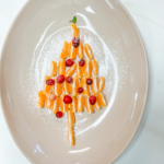 Orange slices arranged to look like a pine tree with cranberries decorated on top to the oranges. All Sprinkled with Powdered sugar. Pinterest Image