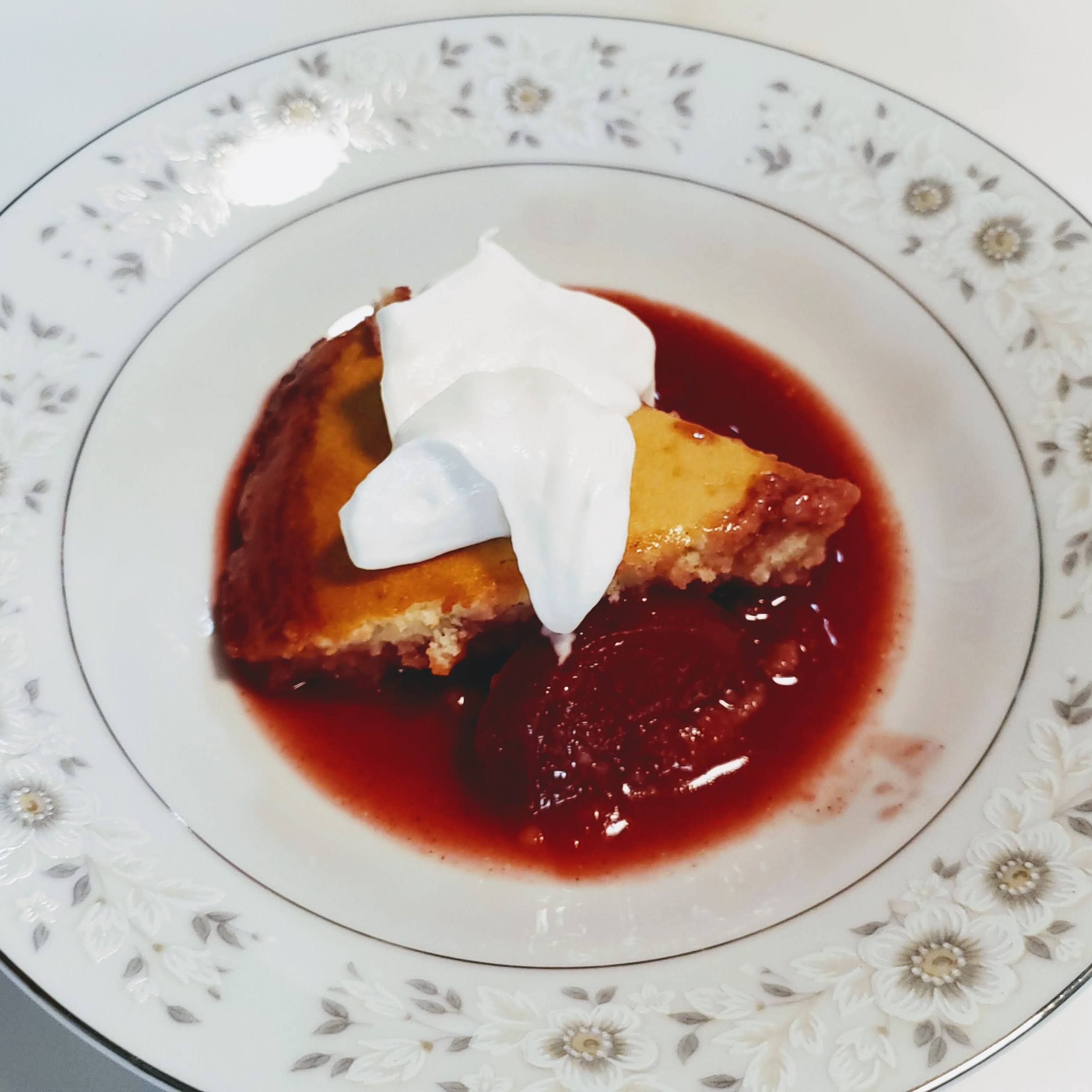 Plum cobbler in a dish with whipped cream on top