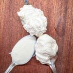 An image of 3 spoons agains a dark wood background to show the texture and stiffness of each style peak of whipped cream.