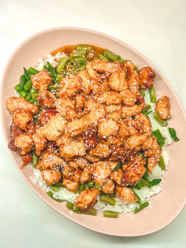 Sesame Orange Chicken on top of green beans and White rice in a Mora Ceramics Serving Platter in Sesame Chai. you Can click on the photo to get this platter.