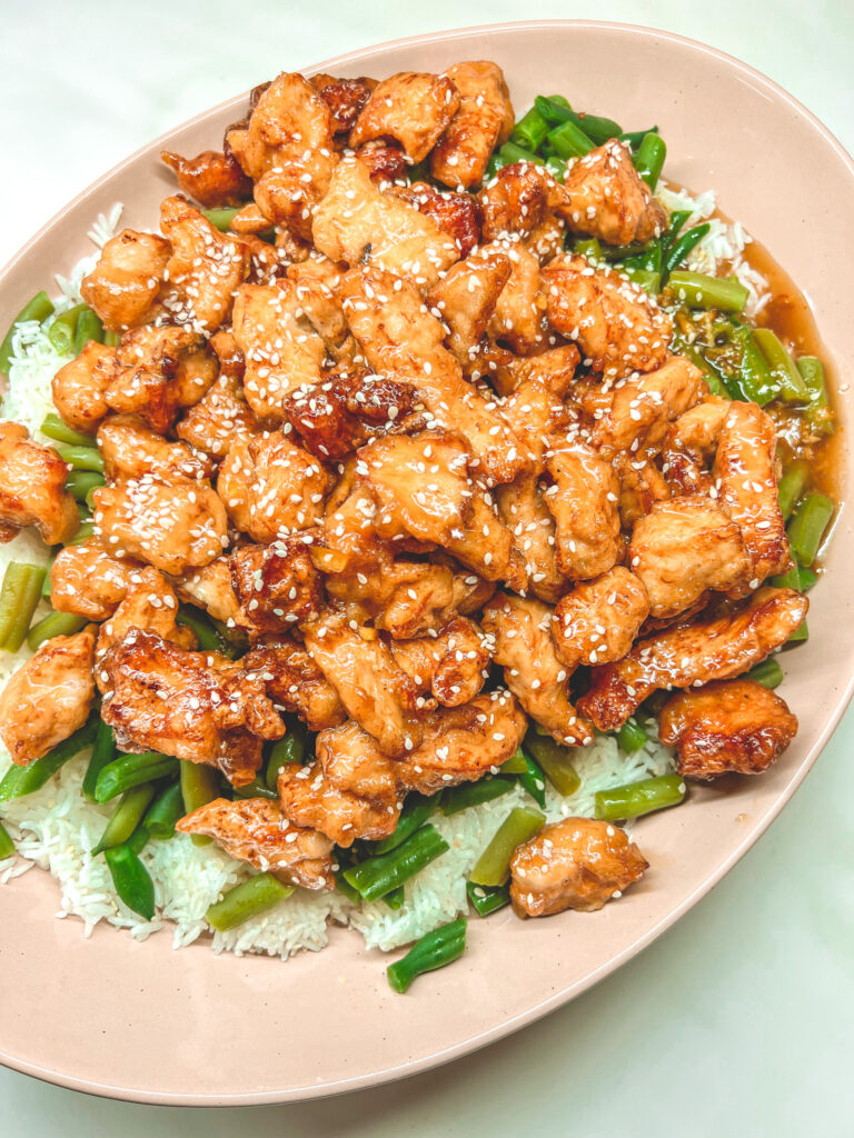 Sesame Orange Chicken on top of green beans and White rice in a Mora Ceramics Serving Platter in Sesame Chai. you Can click on the photo to get this platter.