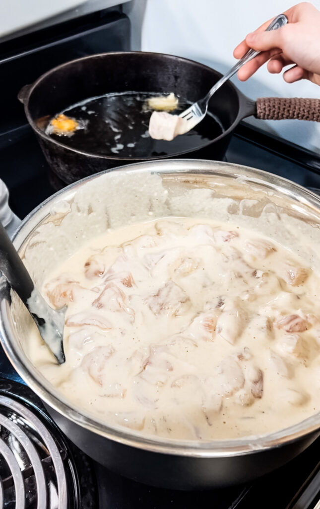 Dropping the chicken into the hot oil with a fork