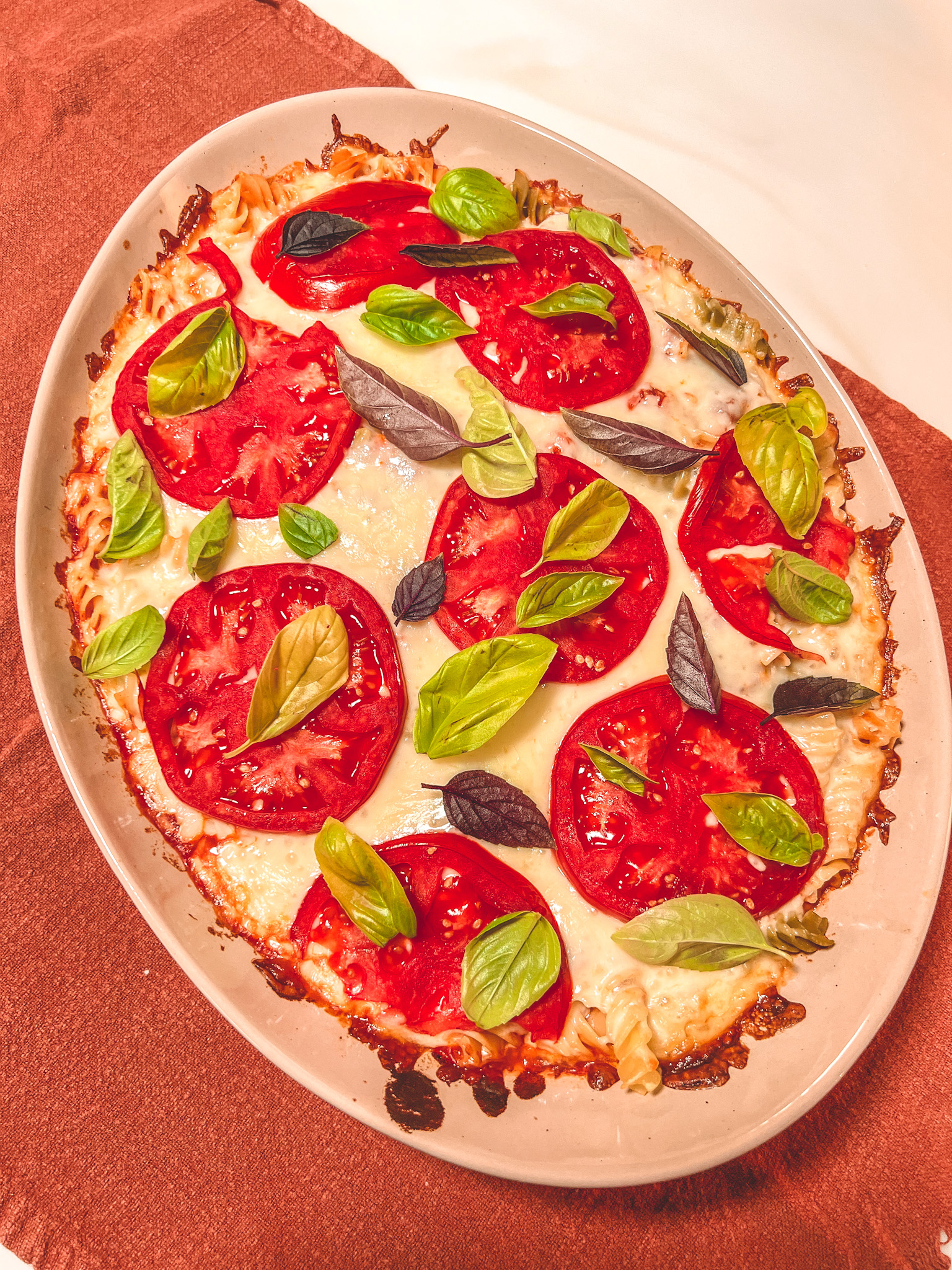 My finish pizza pasta baked, topped with sliced tomatoes and fresh basil.