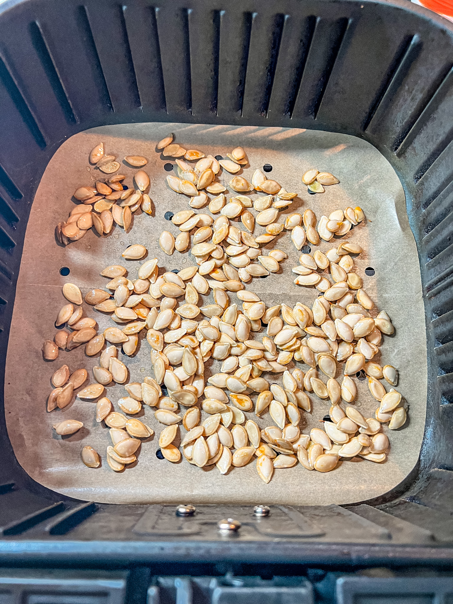 Butternut squash seeds in one layer in an air fryer tray.