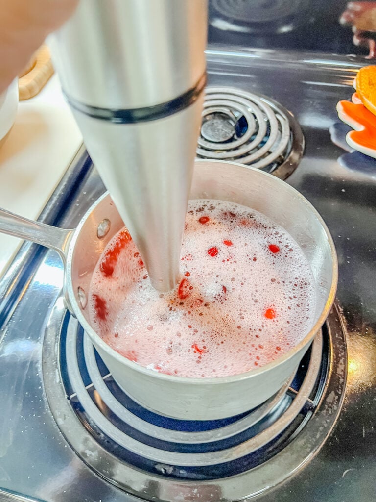 using my immersion blender to blend the the cranberries into a mushy pulp.