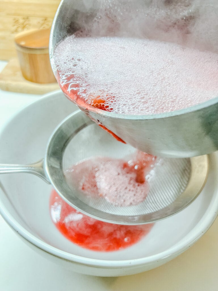 pouring the cranberry purée into a fine mesh strainer that is ver a ceramic (heat safe) bowl.